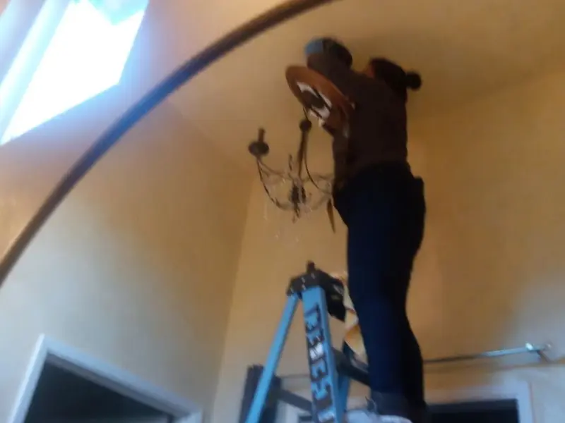 Electrician installing a chandelier in a Okeechobee residence
